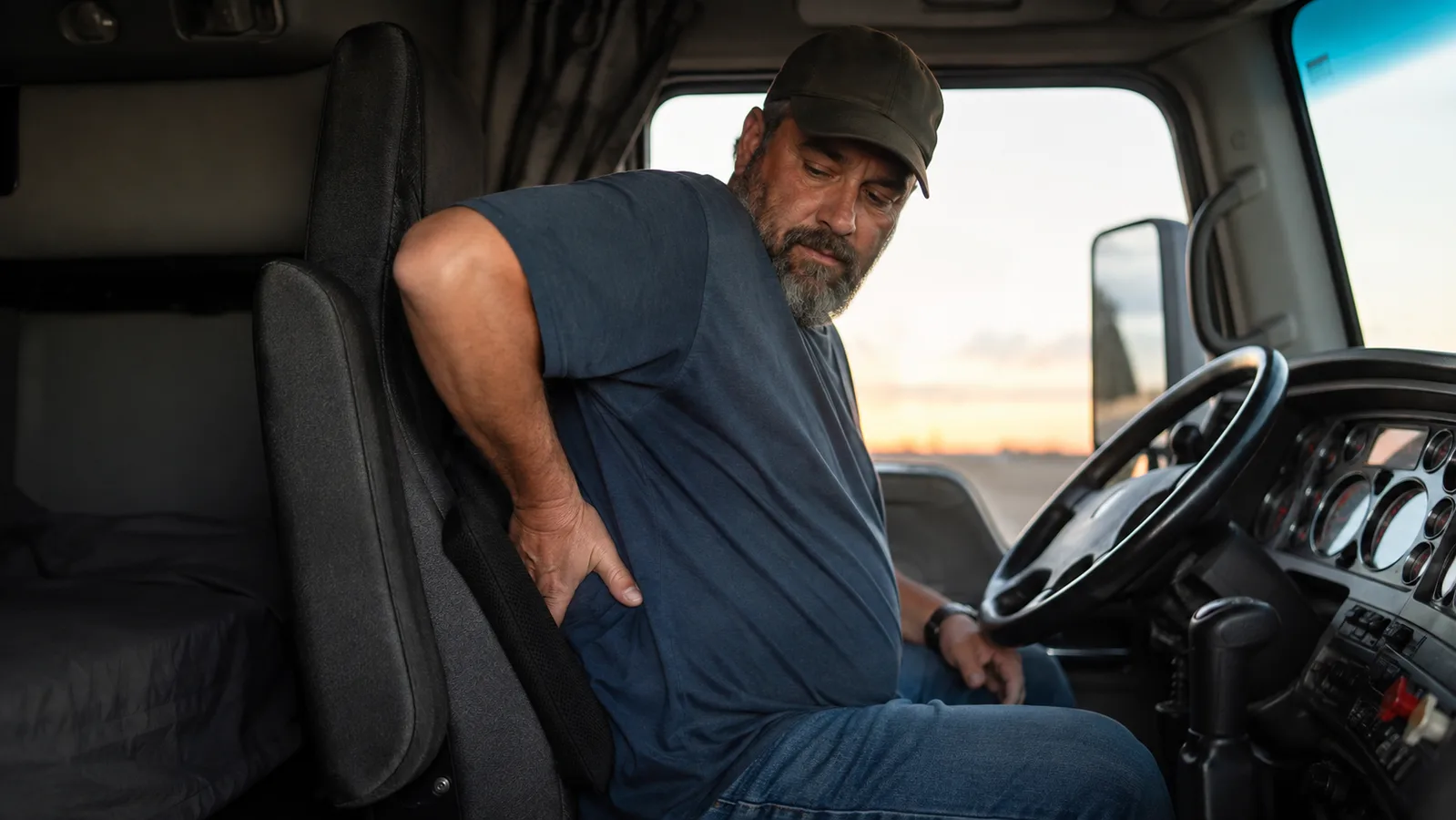 Truck driver adjusting a memory foam lumbar support pillow against the seat back before starting a shift